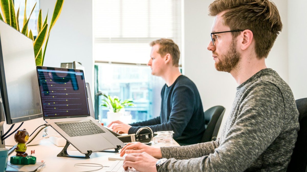 Small business owner reviewing workflow notes and software dashboards on a laptop.