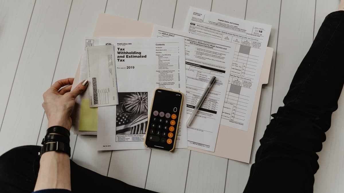 Business owner reviewing an invoice, calculator, and laptop while organizing a service quote.